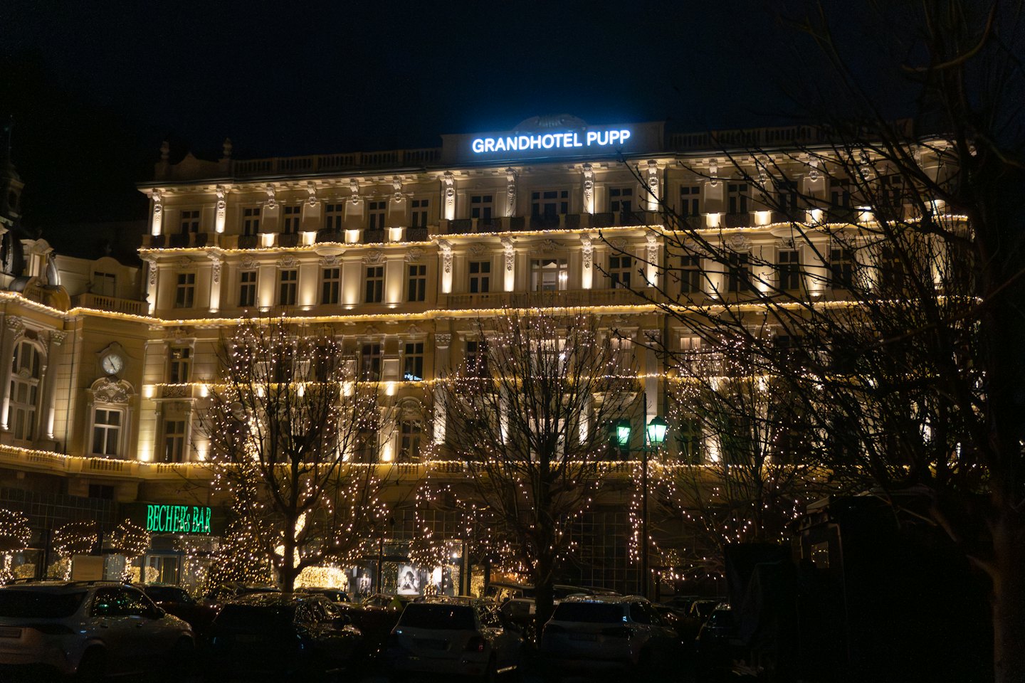 Grand hotel illuminated with festive lights at night.