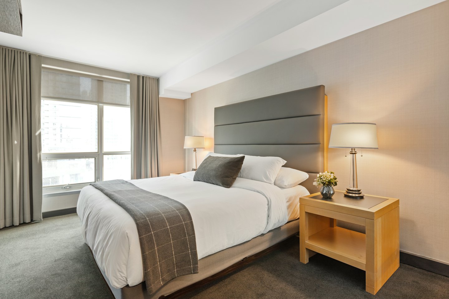 Modern hotel room with a king bed and city view.