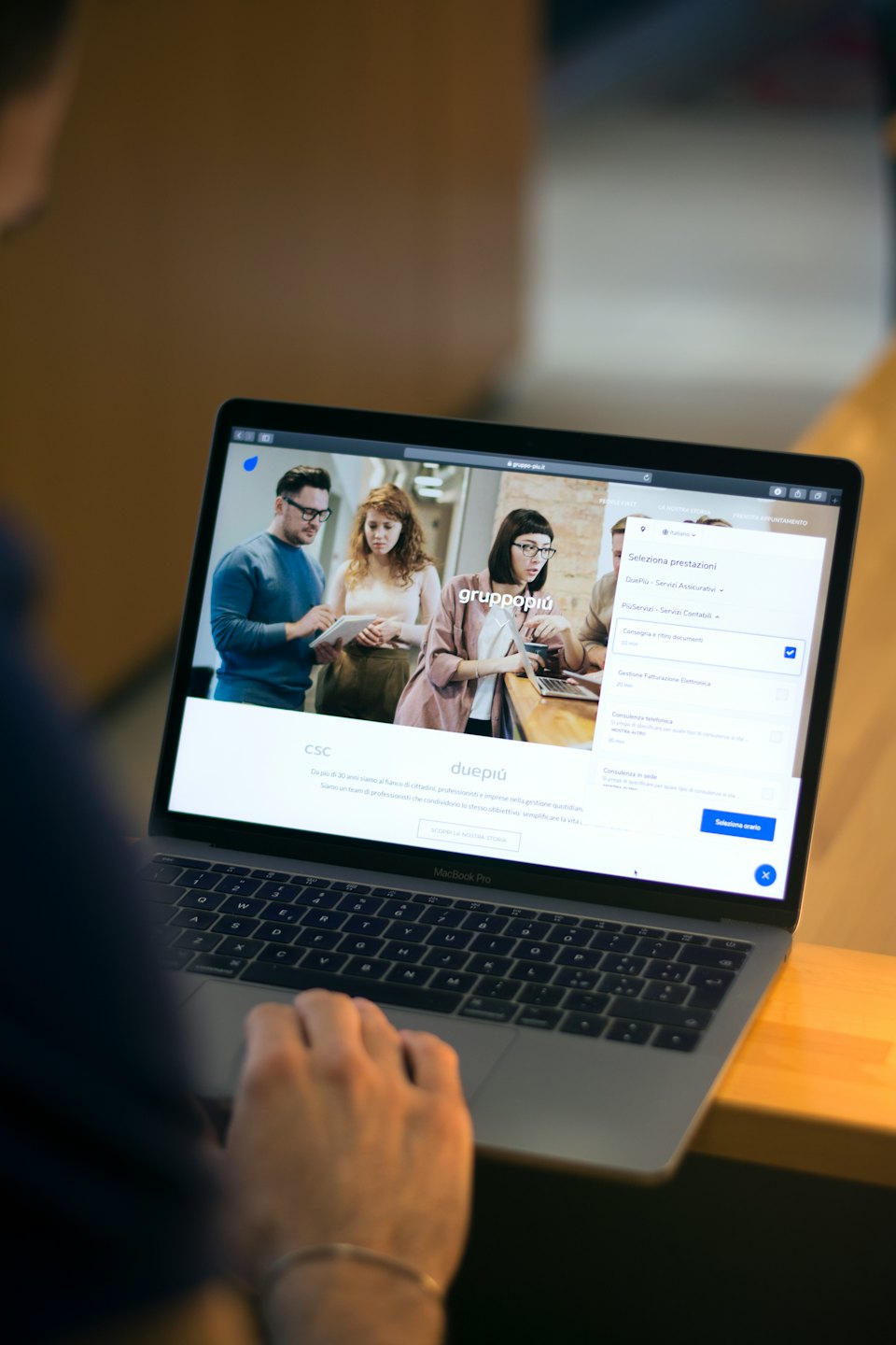Person typing on a silver MacBook Pro laptop indoors.