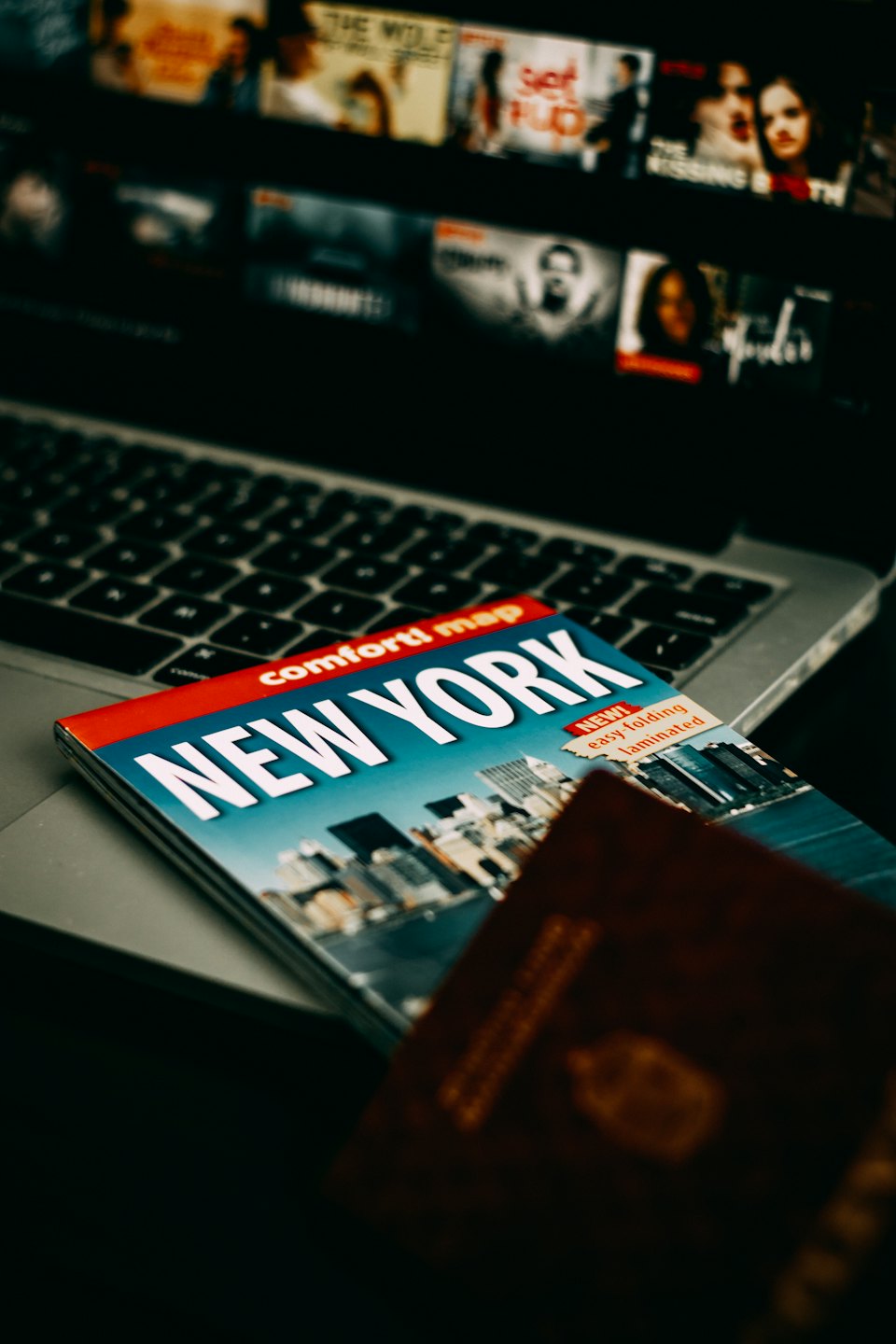 New York travel guide and passport on a laptop.