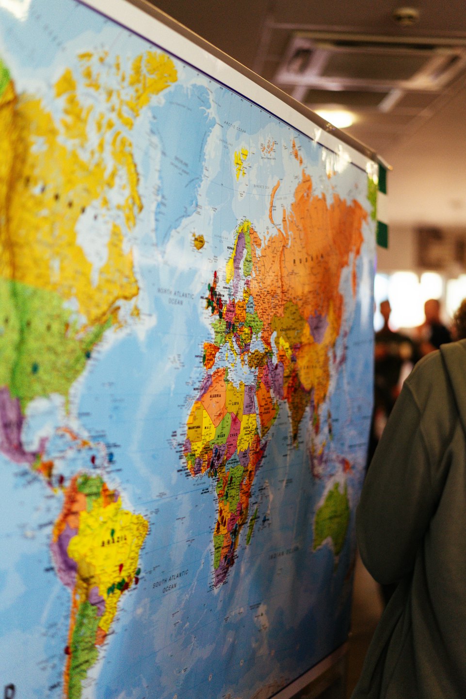 A person looks at pushpins on a world map.