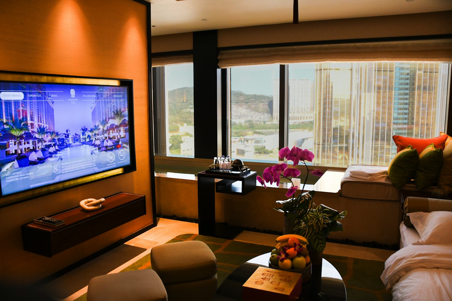 Hotel room with city view, fruit bowl and orchids.